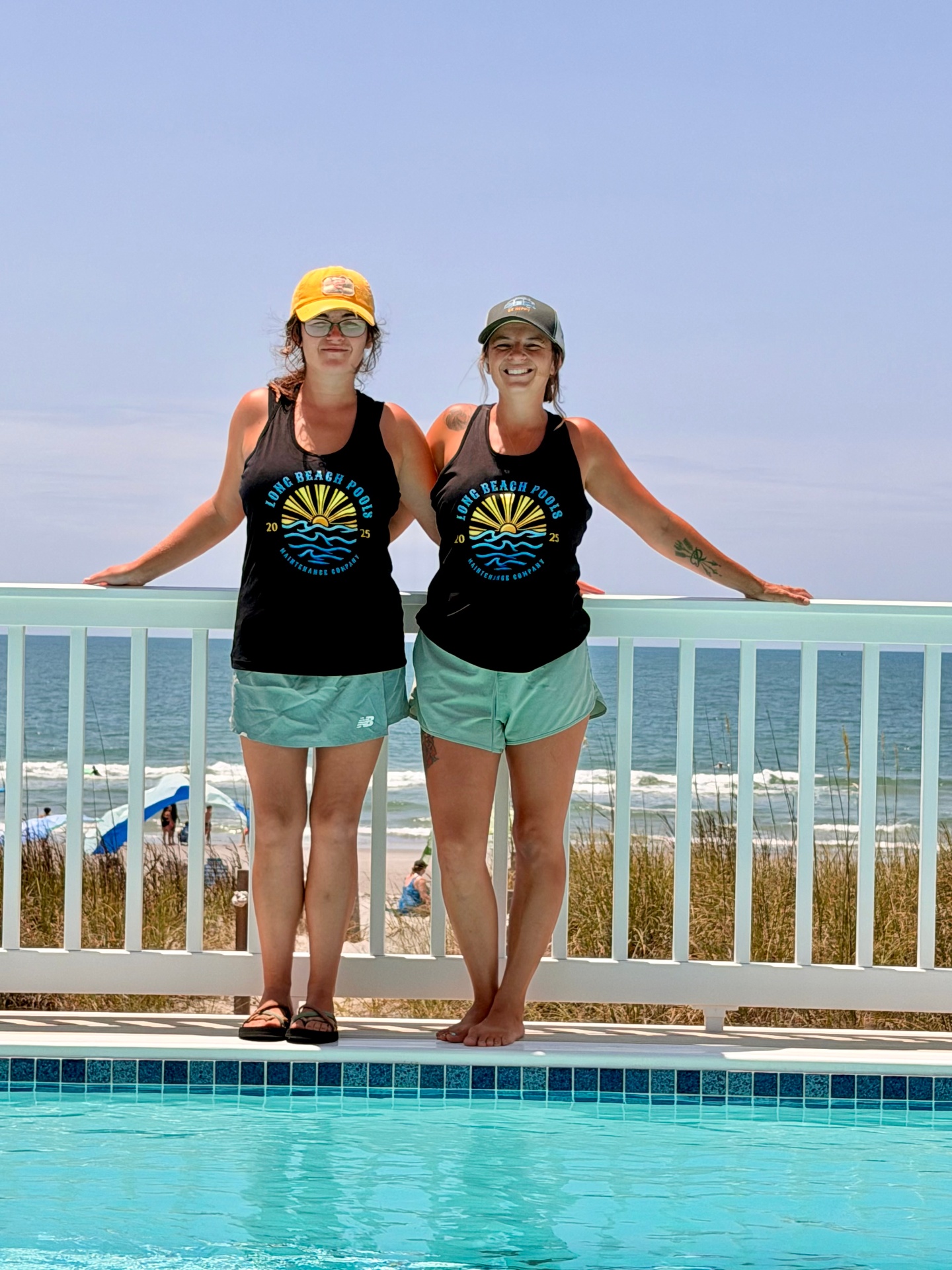 The two sisters behind Long Beach Pools standing poolside by the beach